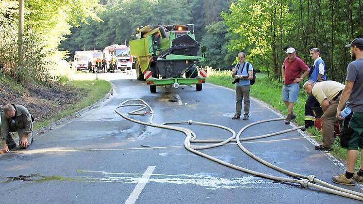 Polizisten aus Ebern messen die Fahrbahnbreite an der Unfallstelle; im Hintergrund der Deutz-Drescher mit angehängtem Mähwerk.  Foto: Ralf Kestel