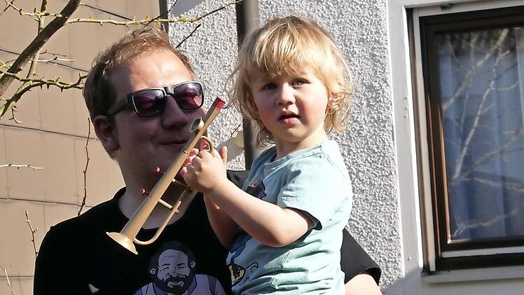 Yannis lauscht mit seinem Papa den Tuba-Tönen am Gartentor.