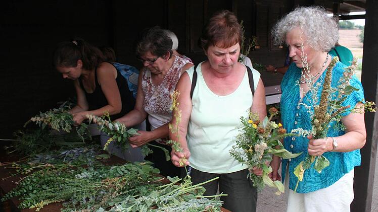 Karin Seubert (rechts) beim Binden des Wurzbüschels mit einer Kursteilnehmerin. Die Königskerze bildet immer den Mittelpunkt des Kräuterbüschels.  Foto: Evi Seeger