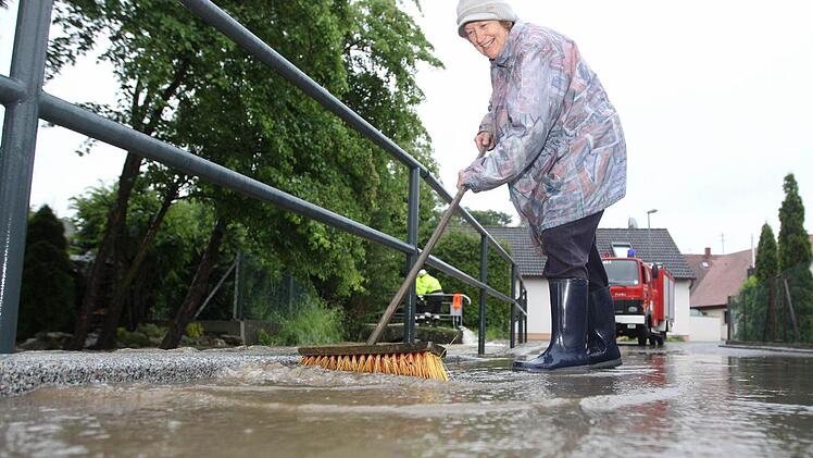Eine Anwohnerin kehrt Wasser von Straße. Foto: News5 / Herse