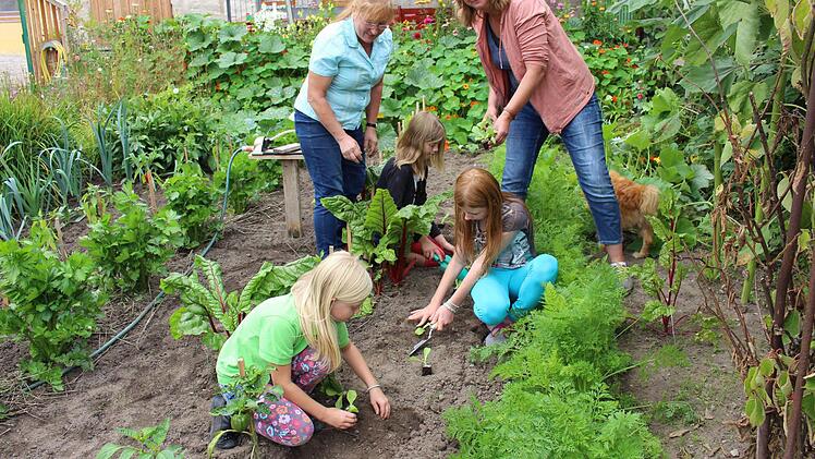 Tina Sickmüller (rechts) und Monika Pflaum pflanzen mit den Kindern Salat.