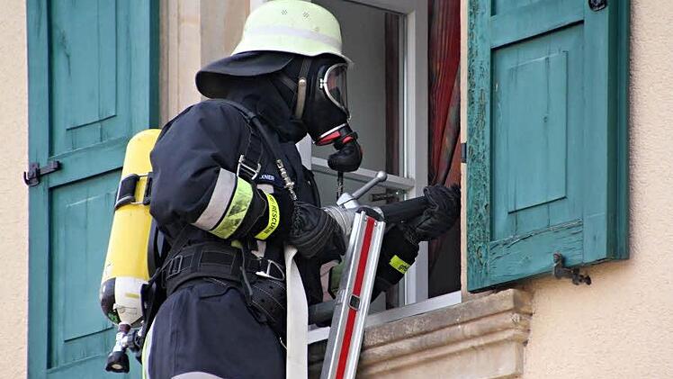 Löschen mit schwerem Atemschutz auf einer Leiter im ersten Stock der alten Schule Gleusdorf.   Foto: Helmut Will