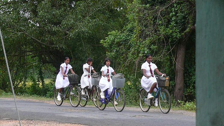 Morgenstund hat Gold im Mund. In ihrer schmucken Schuluniform radeln frühmorgens diese Mädchen in ihre Schule.