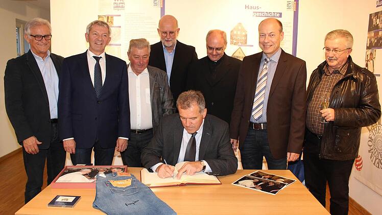 Pommersfeldens Bürgermeister Hans Beck trägt sich in das Goldene Buch des Marktes Buttenheim ein. Hinten stehend: Rainer Dippold, Landrat Johann Kalb, Bürgermeister-Stellvertreter Erich Werner (Buttenheim), Christoph Gatz, Dekan Kilian Kemmer, Bürgermeister Michael Karmann (Buttenheim) und Georg Römer, Vorsitzender des Heimatvereins Höchstadt  Foto: Evi Seeger