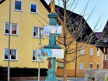 Ein Osterbrunnen der besonderen Art steht in Oberehrenbach: Kinder haben Bilder mit österlichen Motiven gemalt, und diese Gemälde zieren nun den Dorfbrunnen.  Foto: Nadine Trautner