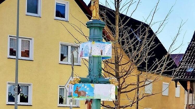 Ein Osterbrunnen der besonderen Art steht in Oberehrenbach: Kinder haben Bilder mit österlichen Motiven gemalt, und diese Gemälde zieren nun den Dorfbrunnen.  Foto: Nadine Trautner