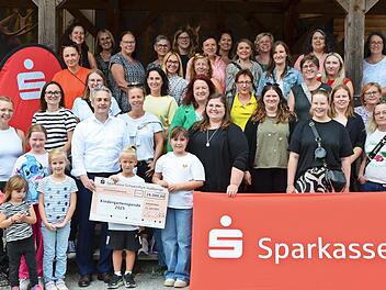 Gruppenbild mit Sparkassen-Logo: (v.l.) Waldpädagogin Sarah Keller, der Vorstandsvorsitzende der Sparkasse Schweinfurt-Haßberge, Peter Schleich, und die Erzieherinnen und Erzieher der geförderten Kindergärten.