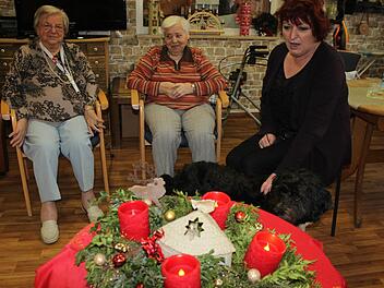 Johanna Auerbeck (r.) und zwei Bewohnerinnen sitzen vor dem Adventskranz mit LED-Leuchten. Foto: Tina Meier