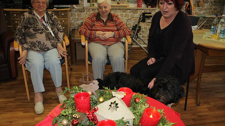 Johanna Auerbeck (r.) und zwei Bewohnerinnen sitzen vor dem Adventskranz mit LED-Leuchten. Foto: Tina Meier