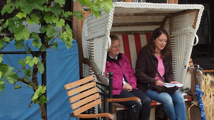 Anja Augustin vom Büchereiteam liest aus der Brigitte-Kolumne "Paulas Garten", in einem Strandkorb sitzend, bei Hedda Hanft im Garten. Foto: Stefanie Karl