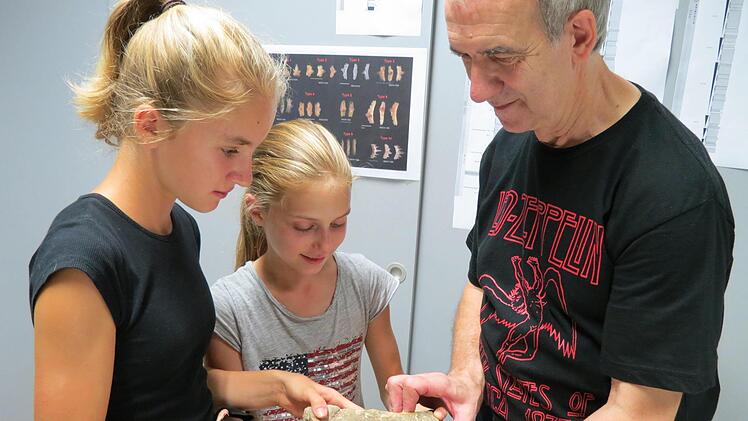 Lucy Rost und Nathalie Bauer haben einen prähistorischen Fund gemacht, den Hobby-Paläontologe Michael Henz erläutert Foto: Doris Bauer