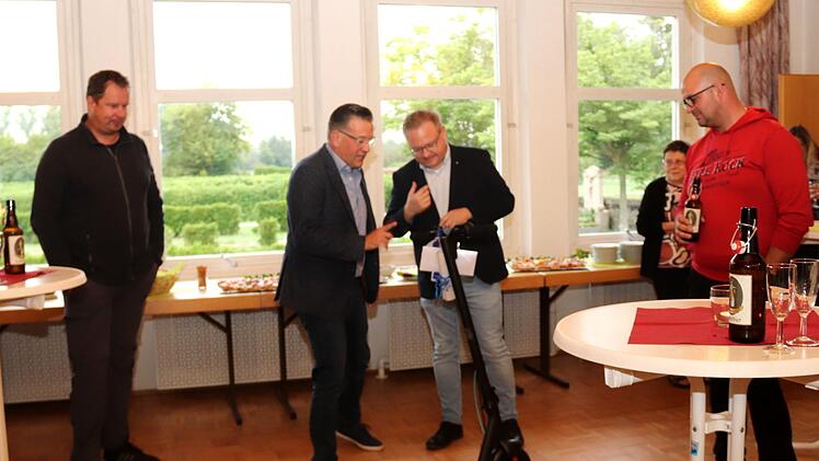 Bürgermeister Karsten Fischkal (zweiter von links) erklärt Pfarrer Ringer (rechts daneben) den Roller.