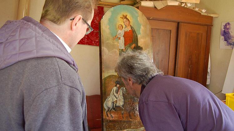 Restaurator Reinhold Müller und Pfarrer Thomas Eschenbacher begutachten das renovierte Bild. Foto: Barbara Oschmann
