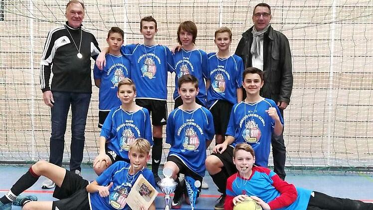 Das siegreiche Team pr&auml;sentierte nach der Siegerehrung stolz den Wanderpokal - (stehend von links) Coach Dr. Jochen Forkel, Tim Wachter (3), Niklas Wich (3), Felix Geigerhilk (3), Konstantin Mayr (6), Direktor Uwe Sch&ouml;nfeld, (kniend von links) Luca Peter (1), Luis Deckelmann, Johannes Sch&uuml;tz (2), (vorne von links) Oliver Schubert (6) und TW Benjamin Rang. In Klammern die jeweils erzielten Tore  Foto: Heike Sch&uuml;lein