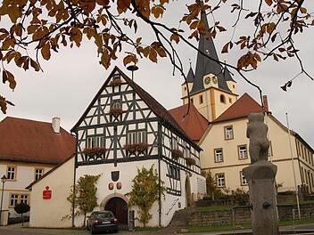 Der "Stettfelder Bär" am Dorfbrunnen hat seinen Blick auf die "gute Stube" von Stettfeld gerichtet mit dem alten Rathaus, der Pfarrkirche Mariä Himmelfahrt und dem Pfarrhaus. Foto: Günther Geiling