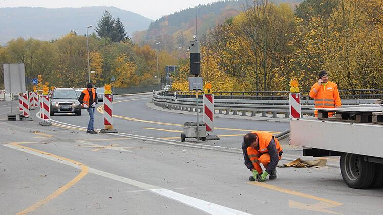 Arbeiter entfernen die gelben Fahrbahnmarkierungen an der Kronacher Südbrücke.  Fotos: Friedwald Schedel
