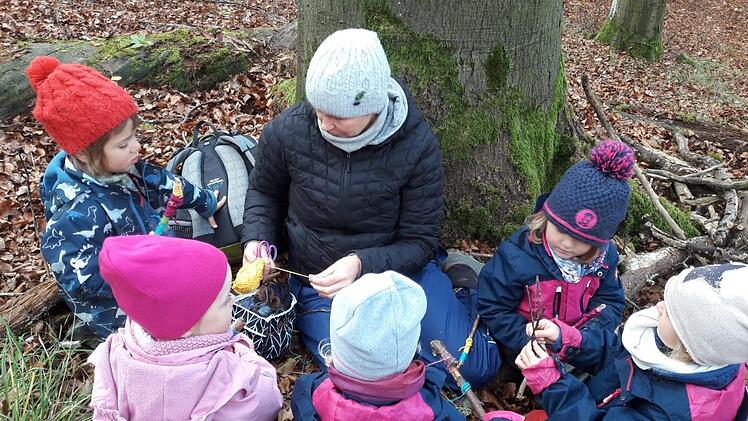 In einem Wald-Kindergarten sind die Mädchen und Jungen jeden Tag an der frischen Luft. Auf diesem Archivbild aus dem Ramsthaler Wald-Kindergarten spielen Kinder am Fuß einer Buche mit Wollfäden und Ästen.