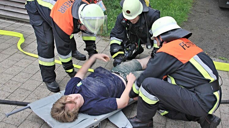 Von Atemschutzträgern aus dem Brandobjekt gerettet, wird die Person zu den Einsatzkräften des BRK gebracht.