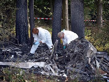 Feuerwehrleute hieven am 5. August 2012 an der Absturzstelle des Kleinflugzeuges in der Nähe des Flugplatz Steinrücken die Reste einer Tragfläche auf einen Anhänger. Für den Untersuchungsbericht konnten nur wenige nicht verbrannte Teile ausgewertet werden.