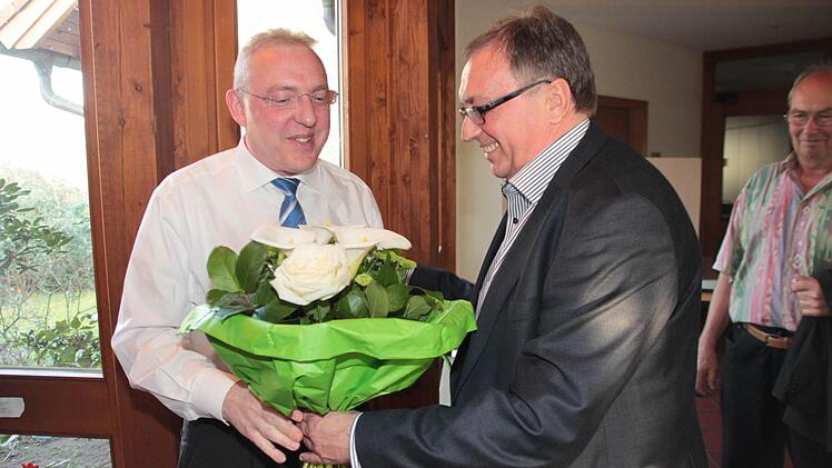 Bürgermeister Dieter Schaar übergibt seinem Nachfolger einen Blumenstrauß.