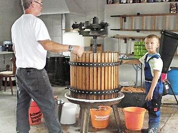 Klein und groß halfen beim Bedienen der Obstpresse beim Apfelfest in Bischofsheim. Hier sind Harald Benkert und Antony tätig.  Foto: Gerold Snater
