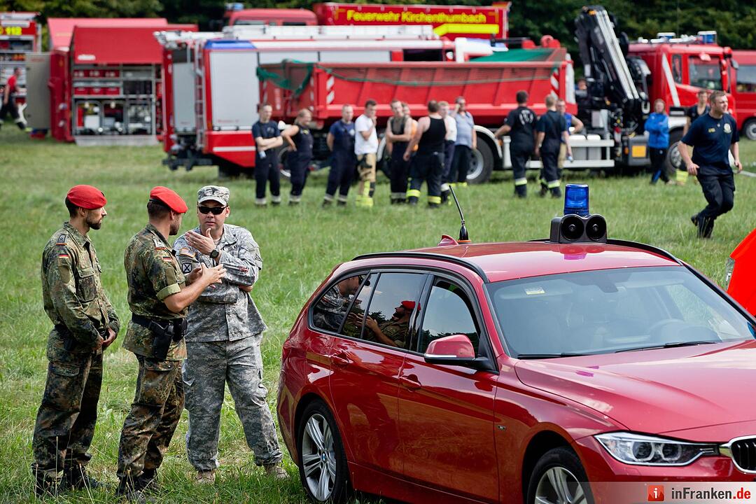 Feldjäger und ein US-Militär unterhalten sich am 11.08.2015 bei Engelmannsreuth (Bayern) am Einsatzzentrum nahe der Absturzstelle eines Kampfjets. Bei Engelmannsreuth ist ein F-16 Kampfjet der US-Streitkräfte abgestürzt. Foto: Daniel Karmann/dpa