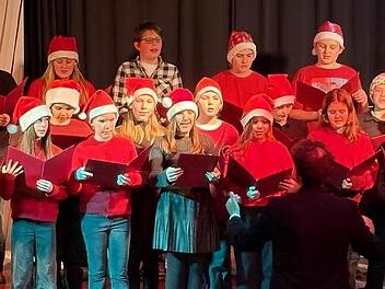 Auch der rot gekleidete Unterstufenchor mit Nikolausm&uuml;tzen unter der Leitung von Christian Moll trat auf.