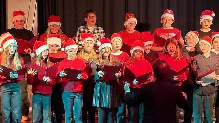 Auch der rot gekleidete Unterstufenchor mit Nikolausm&uuml;tzen unter der Leitung von Christian Moll trat auf.