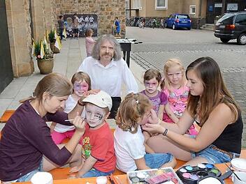 Pater Helmut Haagen (Hintergrund) hatte große Freude an den Aktivitäten seiner Schäflein während der Kirchweihtage. Er trug selbst mit einer gewieften Predigt zur Unterhaltung bei und erhielt dafür viel Applaus in der Herz-Jesu-Kirche. Vorne schminken Julia Neubauer (links) und Celina Suffa (rechts) zwei tüchtige Nachwuchskräfte der Pfarrei. Foto: Karl-Heinz Hofmann