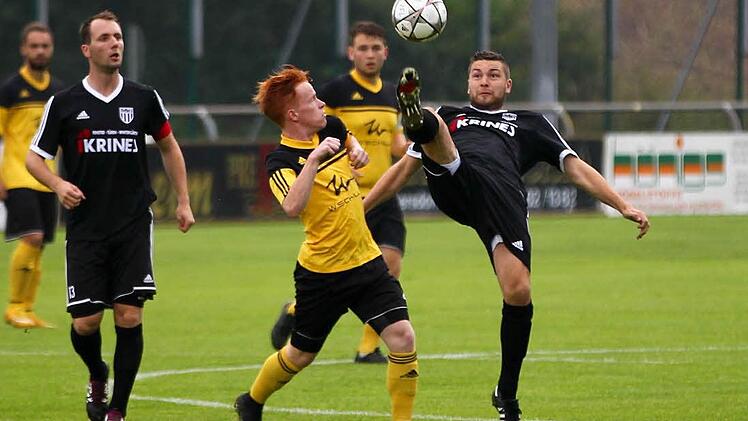Frohnlachs Rene Knie (gelb) hält lieber Abstand als Sands Andre Schmitt mit hohem Bein zum Ball geht