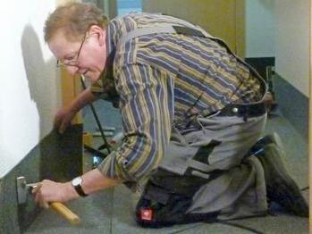 "Haus- und Hof-Raumausstatter" Wolfgang Bauer beim Anbringen der Sockelleiste.