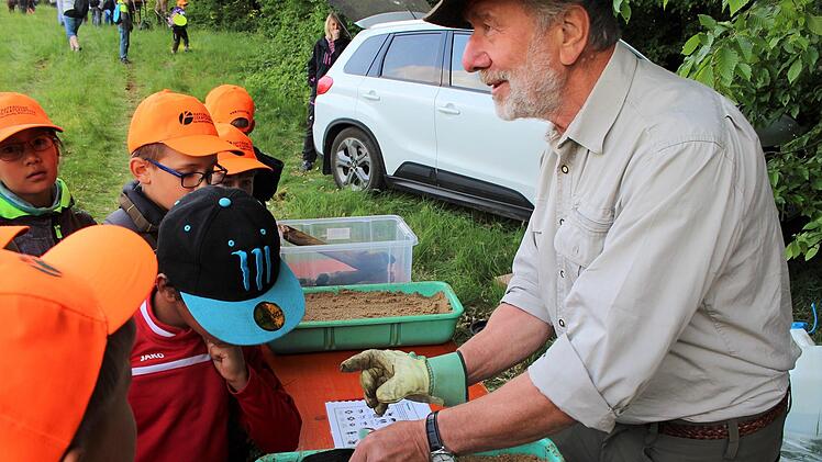 Gerhard Karg zeigt Trittsiegel der verschiedenen Wildtiere. Dabei dürfen die Kinder auch testen.
