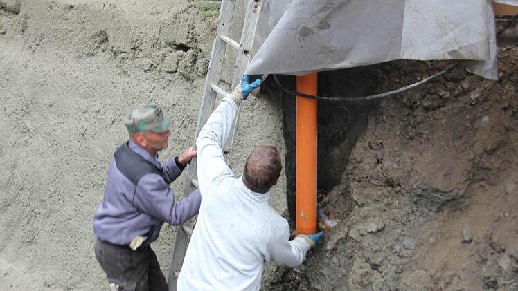 Der Wassereintritt von einer Dachrinne in die Baustellengrube macht den Arbeitern zu schaffen.  Foto: Friedwald Schedel