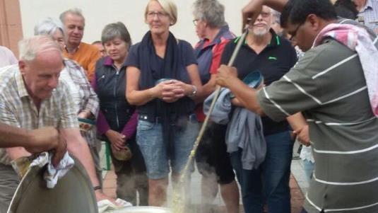 Pater Raja schwingt den großen Kochlöffel am Aschacher Dorfplatz. Er kochte in einem eigens aus Indien mitgebrachten Topf ein Gericht.  Foto: Sigrid Klemke
