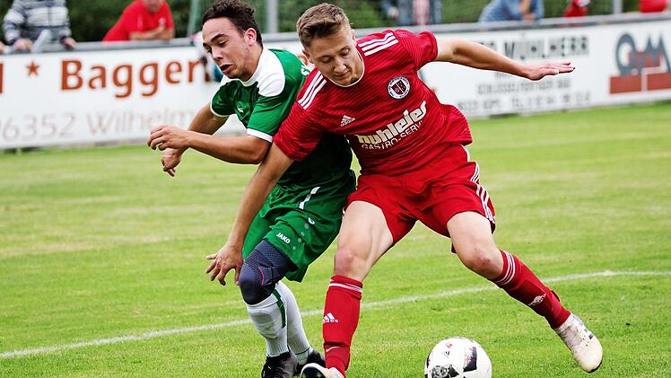Bei der Friesener 0:2-Niederlage im Hinspiel waren die Röllbacher in den Zweikämpfen oftmals cleverer: hier stellt Niklas Scherg (rotes Trikot) den Körper rein und holt sich den Ball gegen Nico Do Adro.  Foto: Weiß