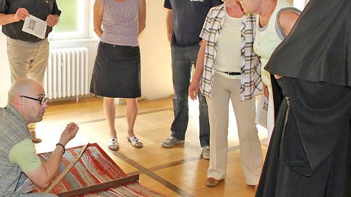 Künstler Thomas Pfarr erläutert den Besuchern gern, wie sein "Buch der Offenbarung" entstanden ist und was es erzählt.  Foto: Martina Straub