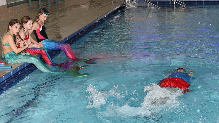 Unter Anleitung von Wassermann Oliver (vorne) lernen Lena, Lara und Maja, wie Meerjungfrauen schwimmen. Foto: Barbara Herbst