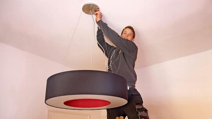 Versteht sein Handwerk: Till Rosenbusch montiert eine Lampe an der Decke eines Gebäudes in der Seifartshofstraße in Coburg. Foto: Sven Dörr