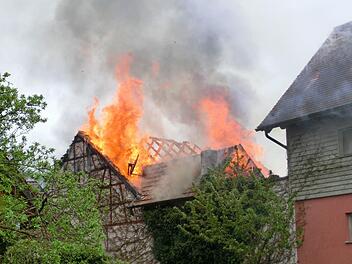 An einer Scheune in der Wülfershausener Straße in Langendorf, direkt neben der örtlichen Schule, geriet am Sonntagnachmittag der Dachstuhl in Brand. Die umliegenden Feuerwehren versuchen ein Übergreifen der Flammen auf Wohnhäuser zu verhindern. Foto: Peter Rauch