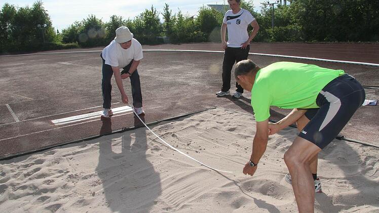 Peter Schmitz und Horst Lauterbach messen nach dem Standweitsprung die Weite.