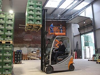 Die neue Halle hat 200 Quadratmeter mehr Platz. Ein Vorteil für die Gabelstapler, wie Geschäftsführer Christian Höfner zeigt. Im Hintergrund, auf der Hebebühne, sind noch die Elektriker am Werk. Fotos: Thomas Heuchling, Jan Koch