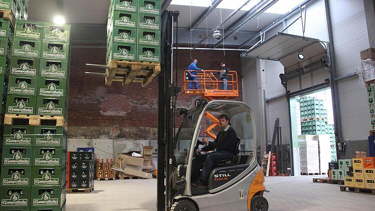 Die neue Halle hat 200 Quadratmeter mehr Platz. Ein Vorteil für die Gabelstapler, wie Geschäftsführer Christian Höfner zeigt. Im Hintergrund, auf der Hebebühne, sind noch die Elektriker am Werk. Fotos: Thomas Heuchling, Jan Koch