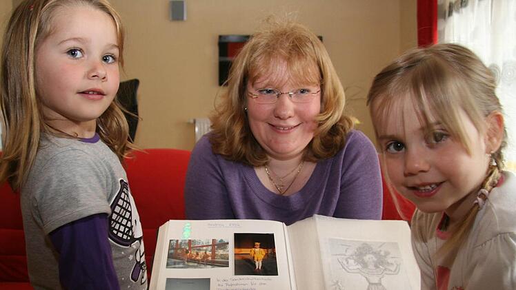 Laura Eck (5/links) und Yasmin Homuth (4/rechts) staunen, wie die Kostüme früher ausgesehen haben. Trainerin Julia Hain zeigt ihnen Aufnahmen aus vergangenen Jahren. Foto: Sonja Adam