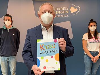 Landrat Thomas Bold (Mitte) zeigt eines der B&uuml;cher "Winterreise 2021", die Manuel M&uuml;ller (links) und Ulrike Abersfelder (rechts) vom KiKiBu-Team mit Kindergartenkindern gestaltet haben.  Foto: Anja Vorndran