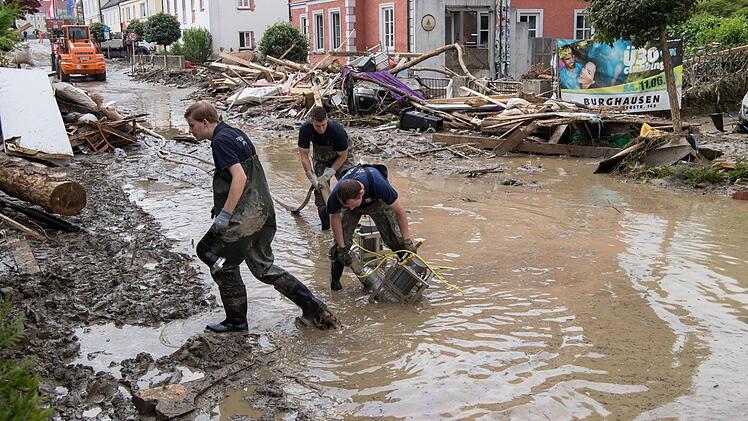 Mitarbeiter des Technischen Hilfswerks (THW) saugen am 3. Juni in der Innenstadt von Simbach am Inn Wasser von der Straße. Die Flutwelle in Niederbayern hat sieben Todesopfer gefordert. Foto: Peter Kneffel/dpa