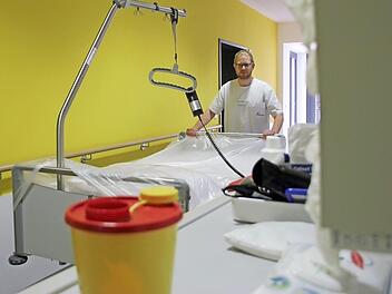 Hygienefachkraft Matthias Fürst mit einem frisch aufbereiten Patientenbett - es ist mit einer Plastikfolie abgedeckt, die eine Kontamination mit Staub und Keimen verhindern soll. Kunststoffe sind im Krankenhausalltag allgegenwärtig, sie tragen zur Einhaltung von Hygienevorschriften bei.