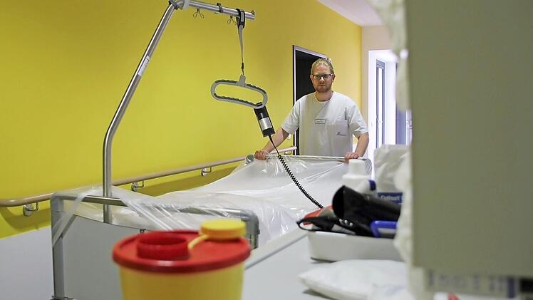 Hygienefachkraft Matthias Fürst mit einem frisch aufbereiten Patientenbett - es ist mit einer Plastikfolie abgedeckt, die eine Kontamination mit Staub und Keimen verhindern soll. Kunststoffe sind im Krankenhausalltag allgegenwärtig, sie tragen zur Einhaltung von Hygienevorschriften bei.