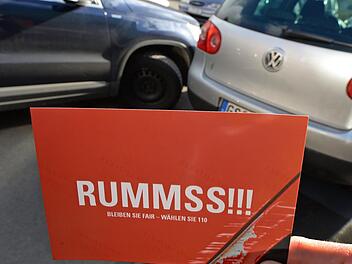 «Rummss!!!» steht auf einer Postkarte, die in Hannover (Niedersachsen) vor eine gestellte Unfallsituation mit zwei Personenwagen gehalten wird. «Bleiben Sie fair - wählen Sie 110» heißt es auf der Karte, die auf der Rückseite Tipps zum richtigen Verhalten nach einem Parkplatzrempler oder einer Schramme mit dem Einkaufswagen gibt. Wer einen Unfall verursacht, muss auch nach Blechschäden die Polizei rufen und warten. Experten halten die Regelung für überholt. Foto: Holger Hollemann/dpa