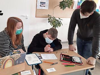 Auch Nils muss Maske tragen. Über die Schulter schauen ihm seine Schulbegleiterin Janine Schröter und sein Klassenlehrer Marco Jahns.
