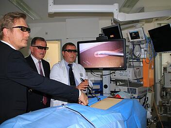 Chefarzt Dr. Boris Kardziev (rechts) und der leitende Oberarzt Dr, Aljaž Hojski (links) demonstrieren Bezirkstagspräsident Erwin Dotzel die videoassistierte Thoraxchirurgie an einer Versuchspuppe. 3D-Brillen sorgen für eine dreidimensionale Darstellung am Bildschirm. Foto: Beudert